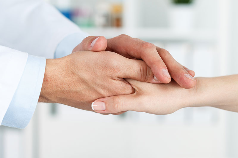 Medical professional holding a patient's hand.