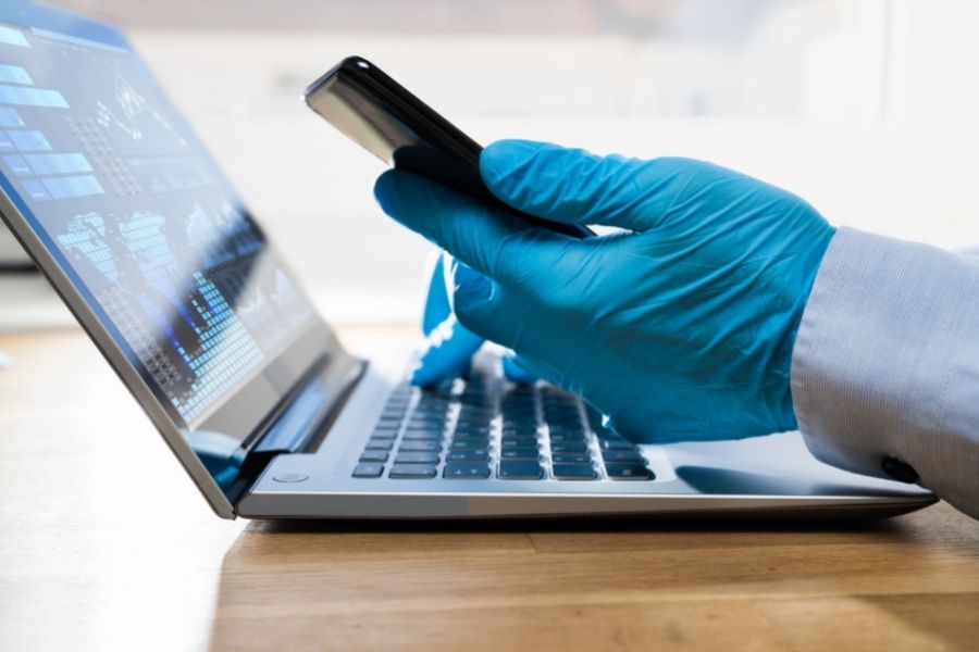 Doctor wearing gloves on computer and phone