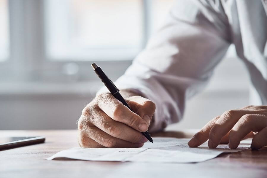 Image of a hand signing a contract